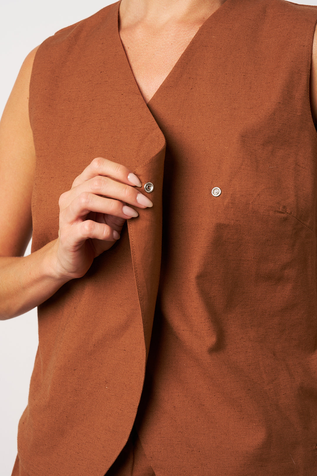 Brown sleeveless top with buttons on a plain background