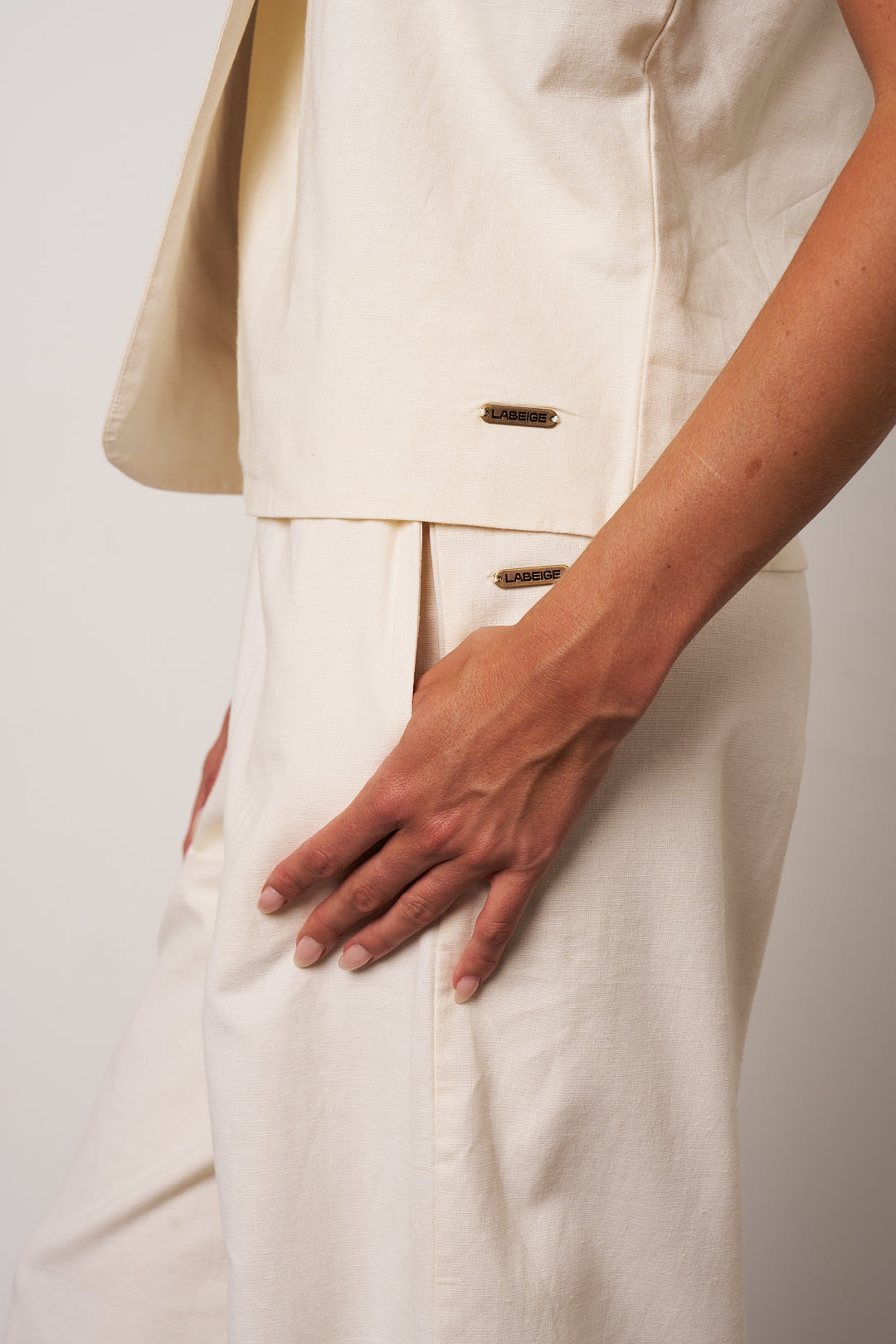 Person wearing a beige suit with a plain background