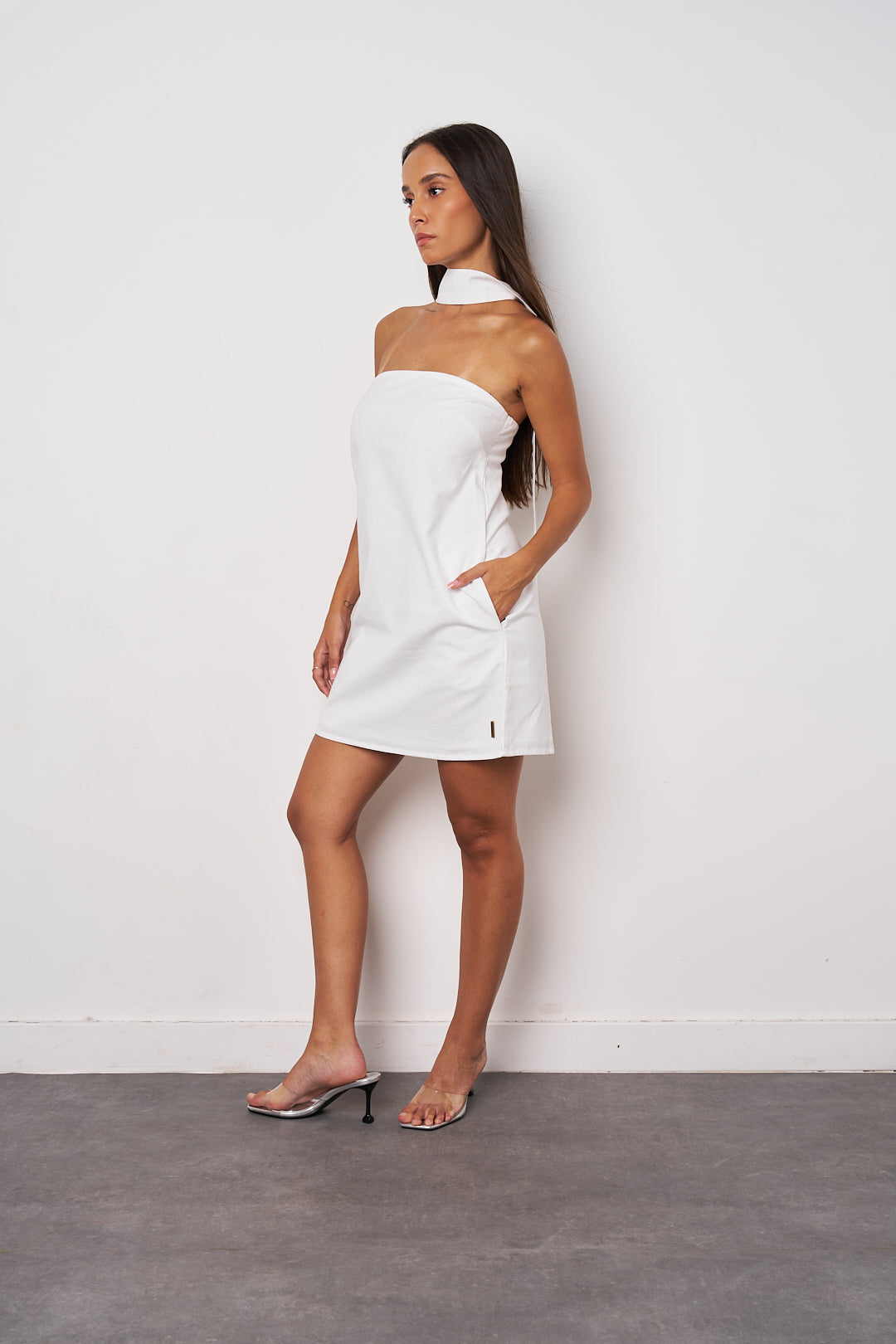 Woman wearing a white strapless dress against a plain background