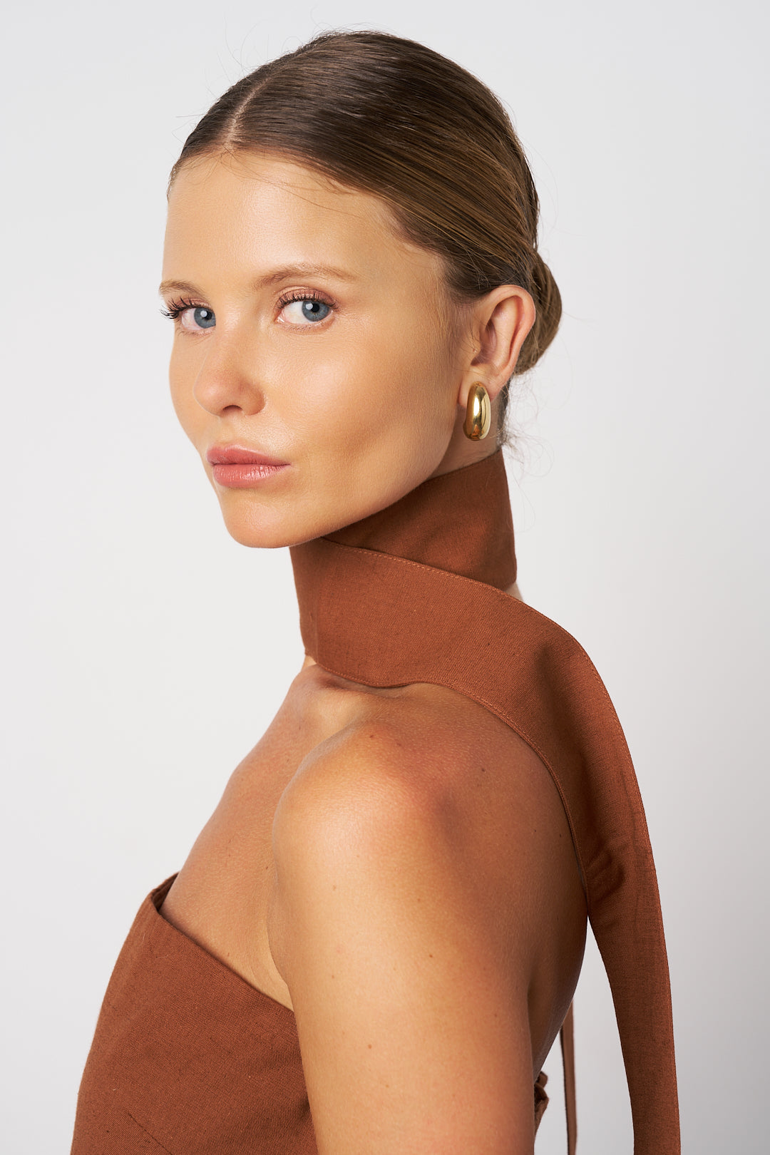 Woman wearing a brown top with a plain background