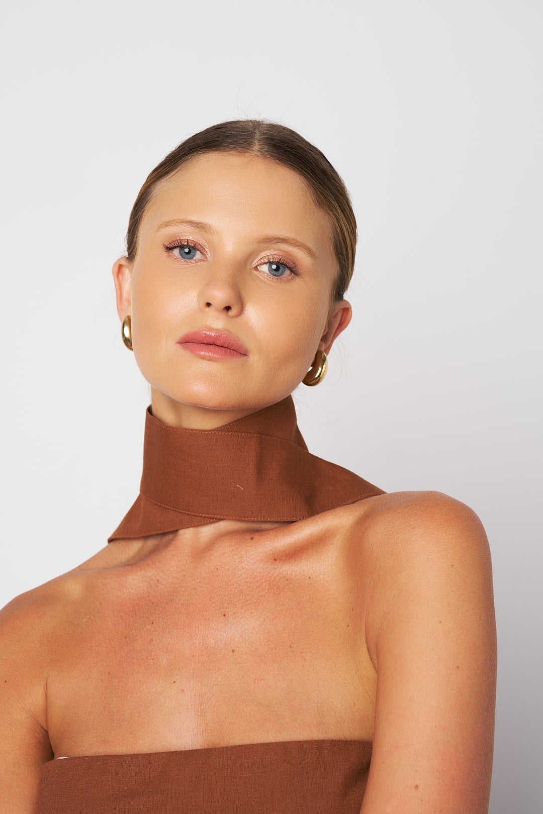 Woman wearing a brown high-neck top against a white background