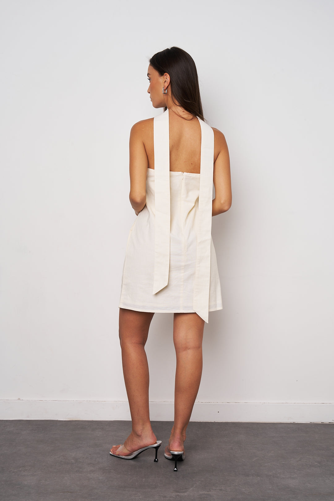 Woman wearing a white sleeveless dress against a plain background