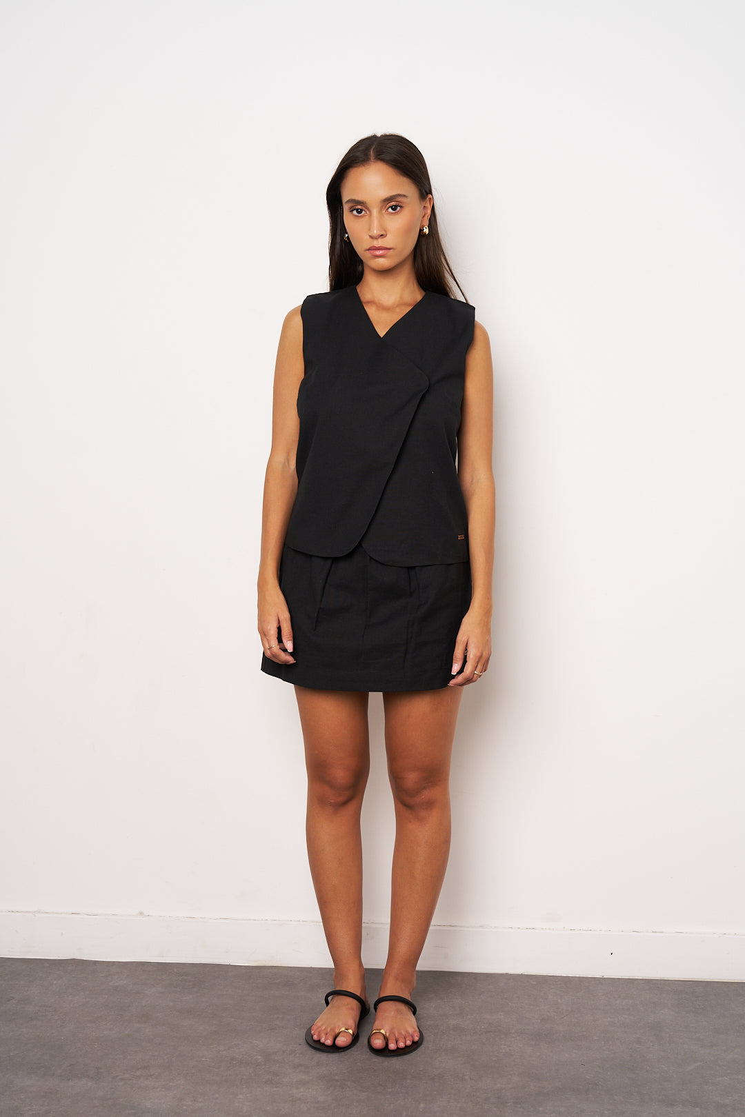 Woman wearing a black sleeveless top and skirt against a white background