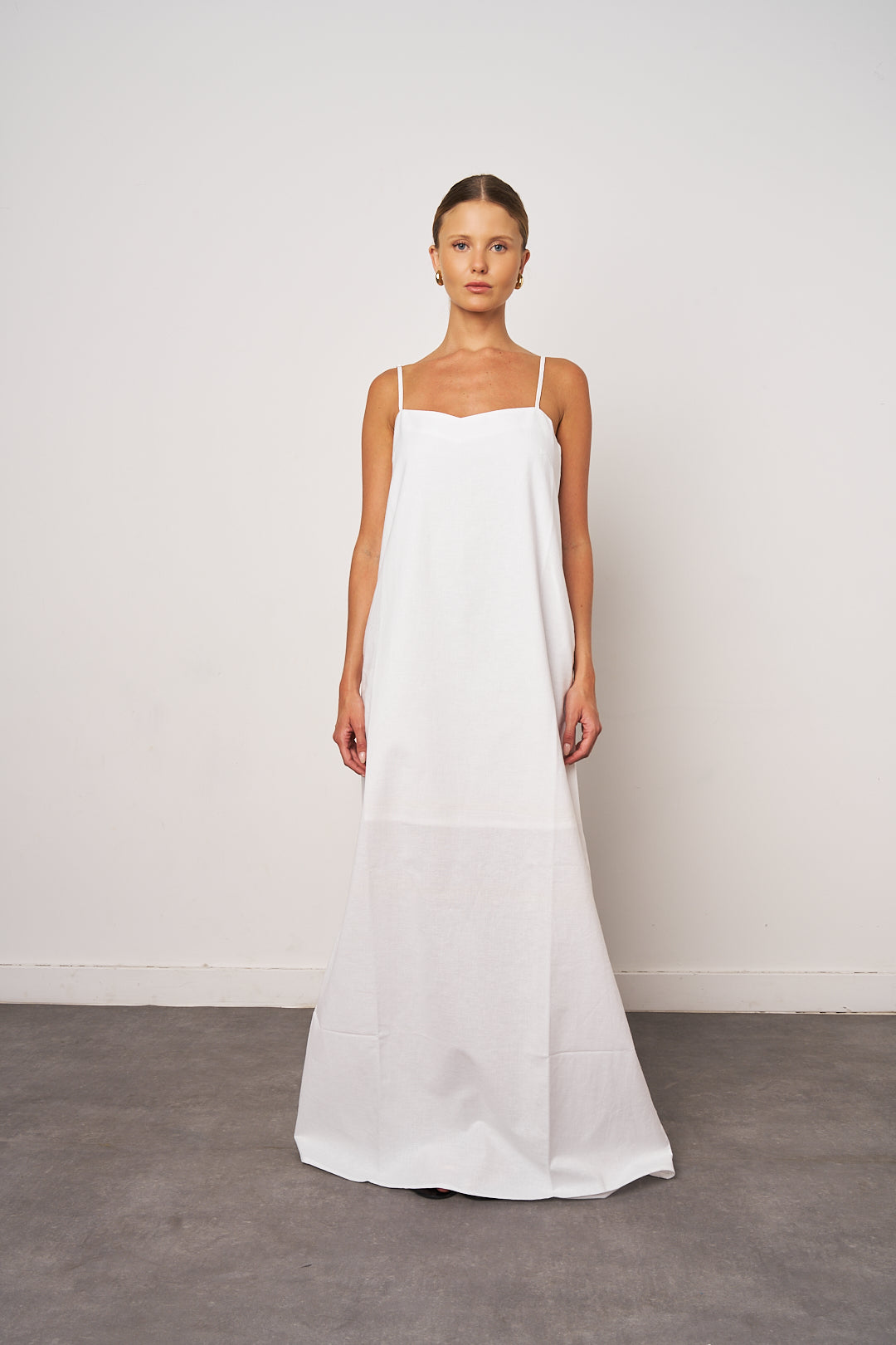 Woman wearing a white slip dress against a plain background