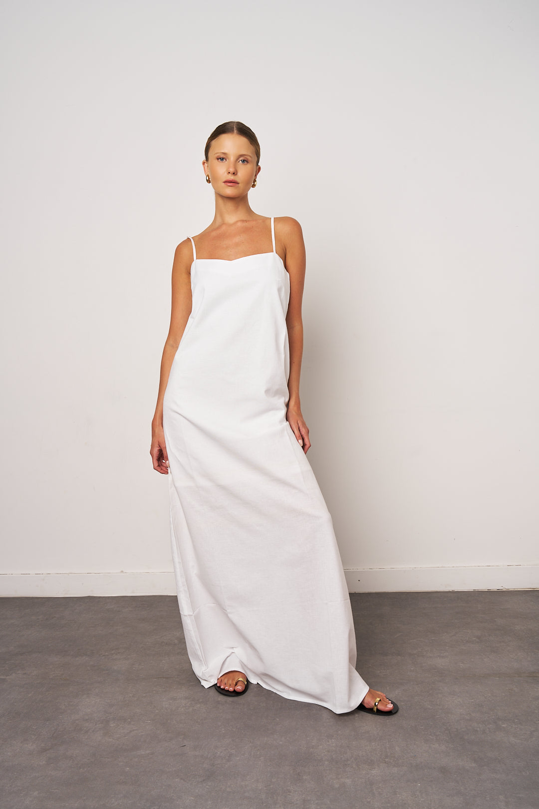 Woman wearing a white slip dress against a plain background