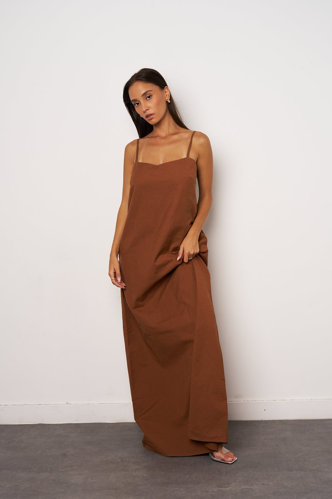 Woman wearing a brown maxi dress against a white background