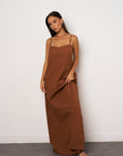 Woman wearing a brown maxi dress against a white background