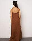 Woman wearing a brown maxi dress against a white background back look