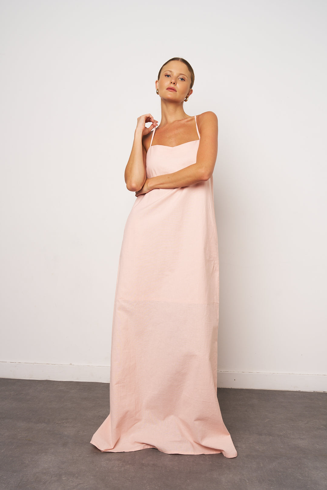 Woman wearing a long pink dress against a white background