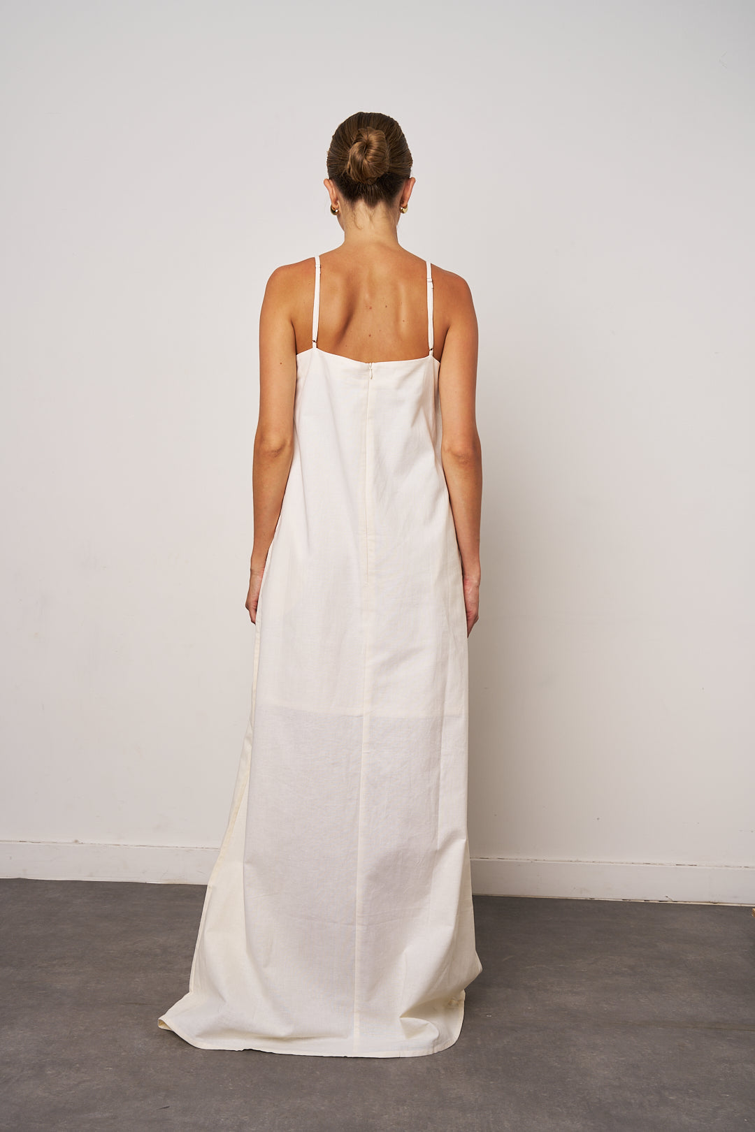 Woman wearing a long white dress against a plain background