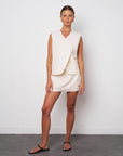 Woman wearing a white sleeveless dress against a plain background