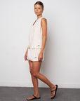 Woman wearing a white sleeveless dress against a plain background
