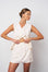 Woman wearing a white sleeveless dress against a plain background