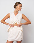 Woman wearing a white sleeveless dress against a plain background