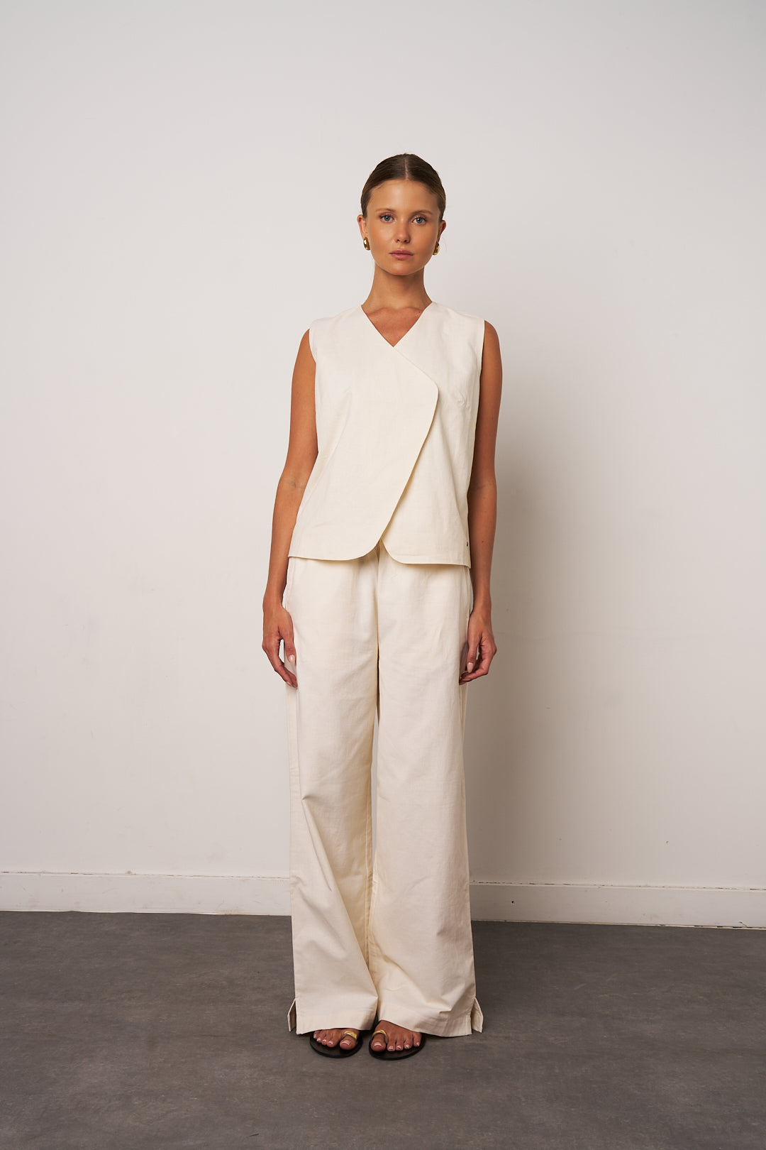 Woman wearing a cream-colored outfit against a plain background