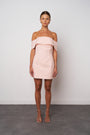 Model wearing a light pink off-shoulder dress against a plain background