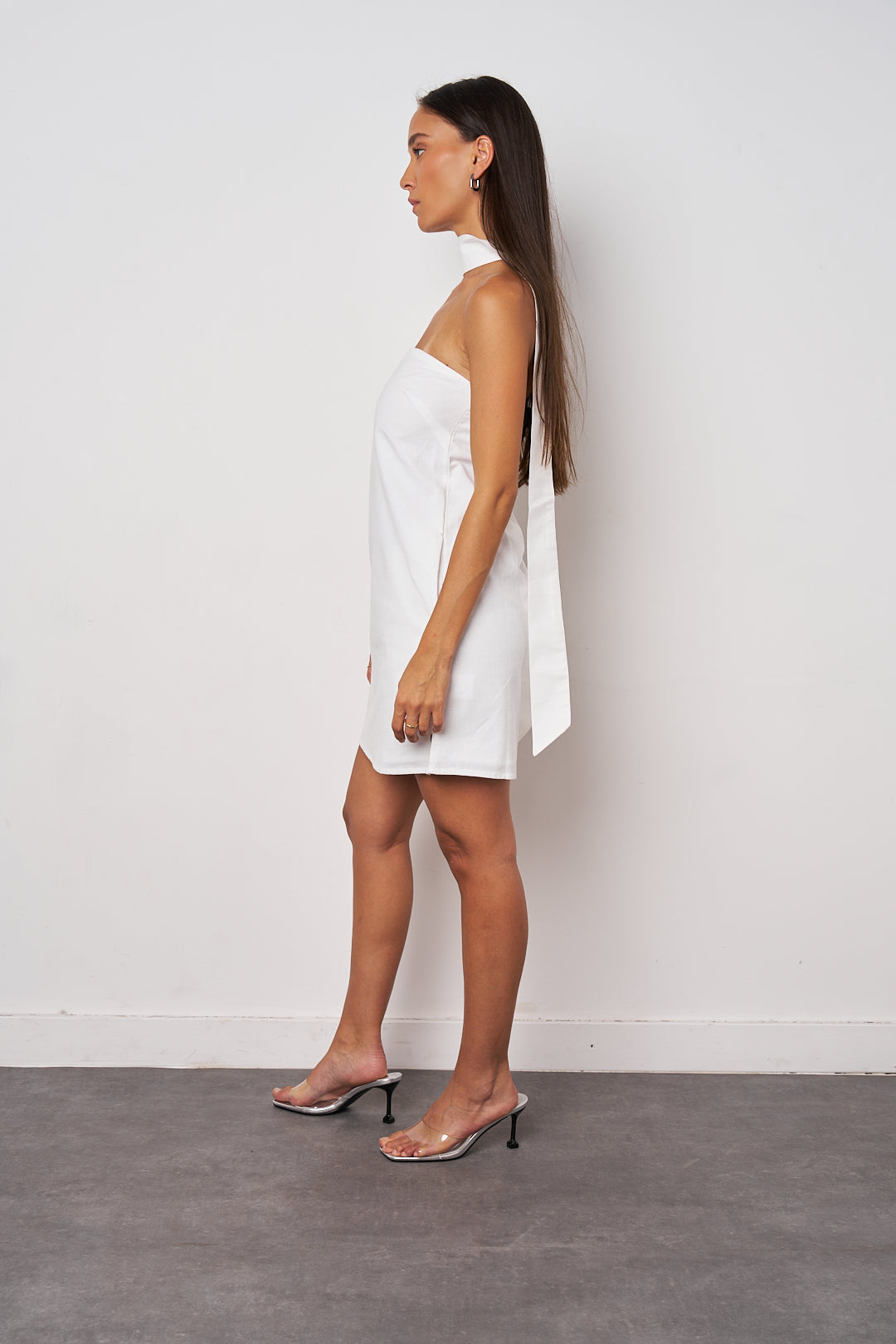 Woman wearing a white strapless dress against a plain background