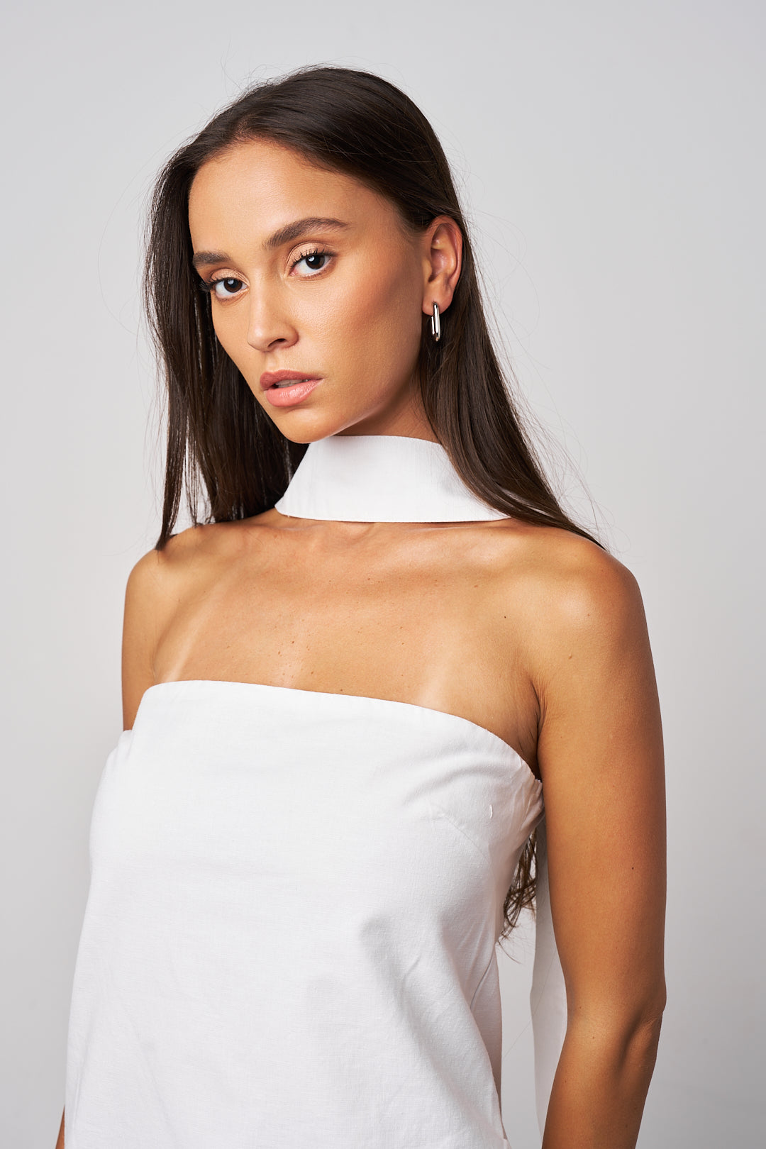 Woman wearing a white strapless dress against a plain background