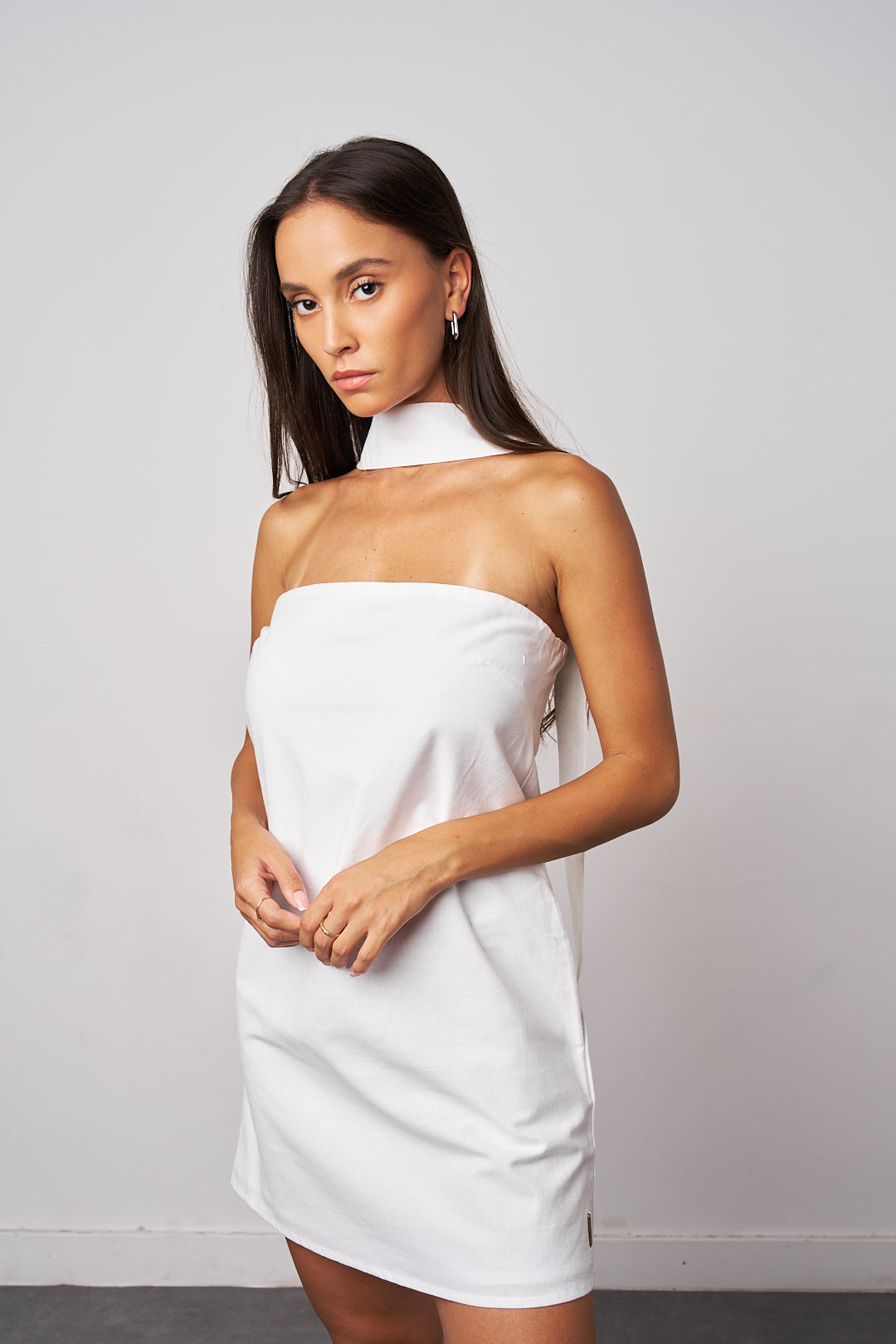 Woman wearing a white strapless dress against a plain background