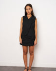 Woman wearing a black sleeveless top and skirt against a white background