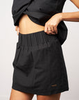 Person wearing black shorts and a black top against a plain background