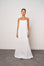 Woman wearing a white slip dress against a plain background