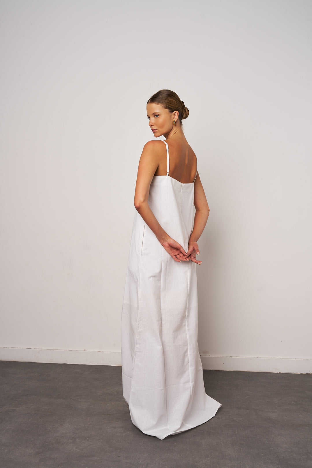 Woman wearing a white wedding dress against a plain background
