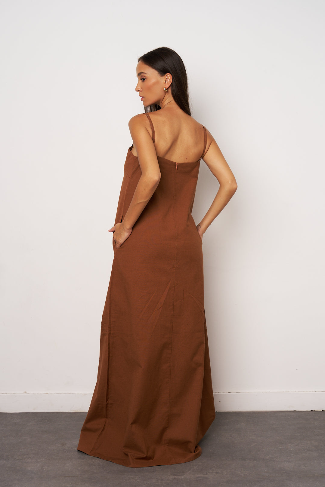 Woman wearing a brown dress against a white background back look