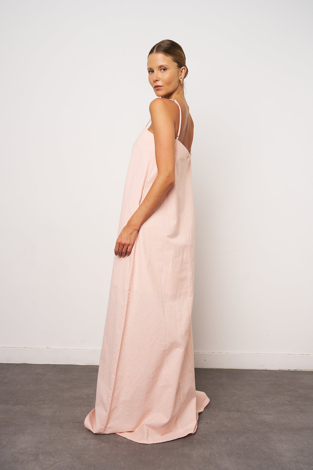 Woman wearing a long pink dress against a white background