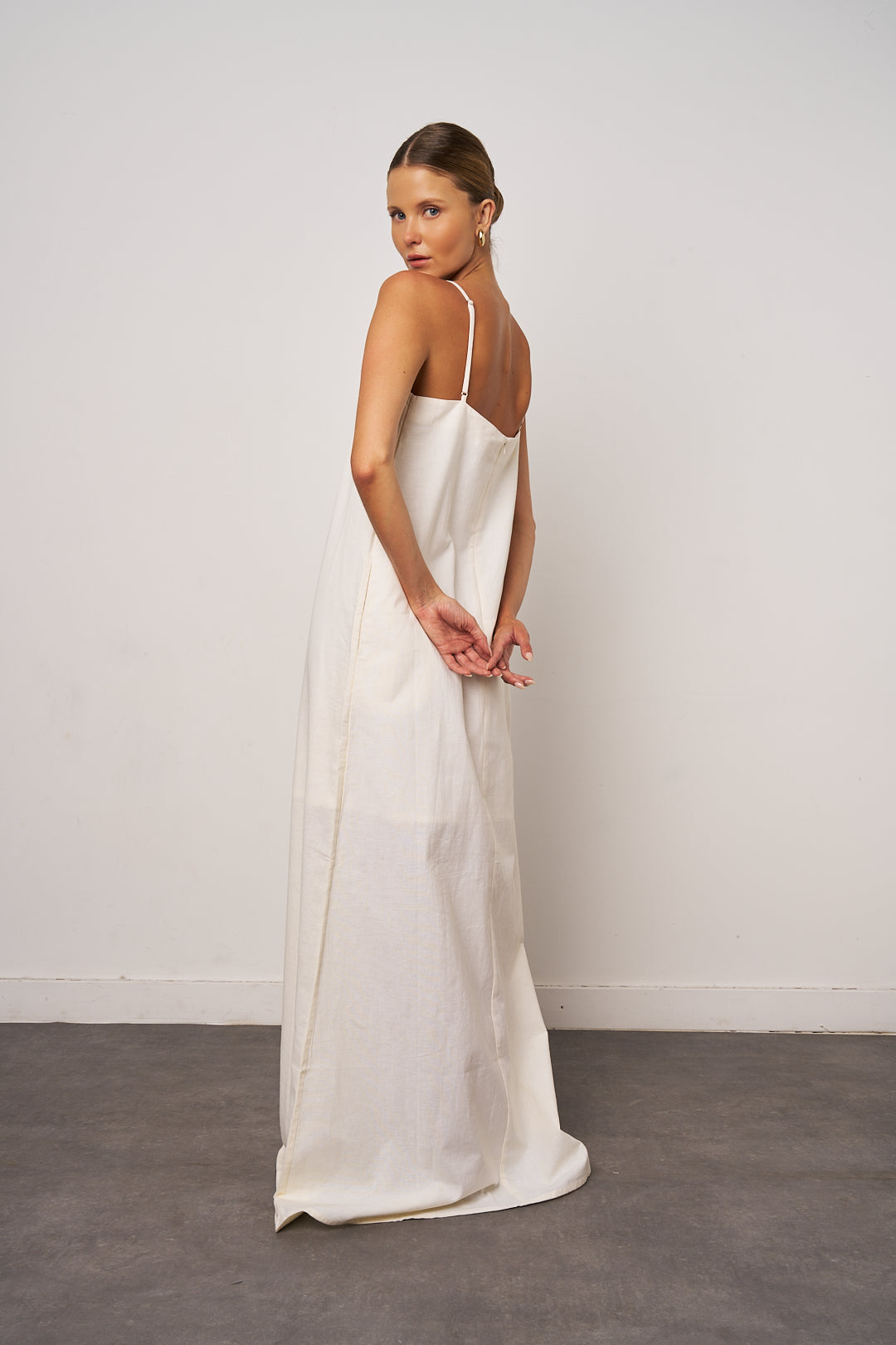 Woman wearing a white slip dress against a plain background