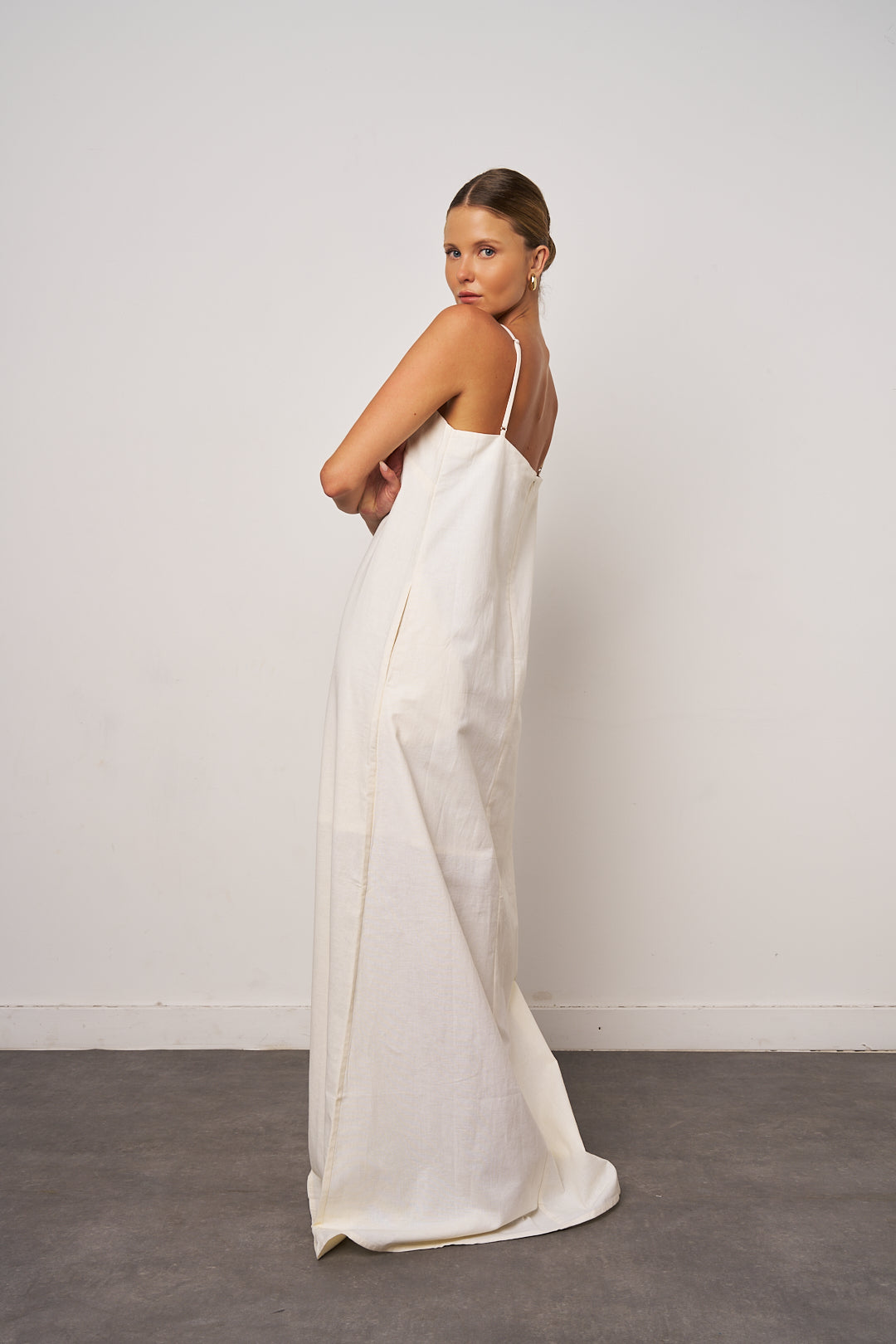 Woman wearing a white slip dress against a plain background